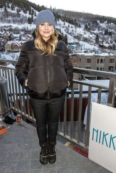Kristen Bell bundled up in a brown puffer jacket, black snow boots, and a grey knit beanie.
Kristen Bell bundled up in a brown puffer jacket, black snow boots, and a grey knit beanie.