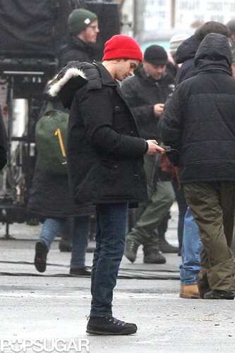 Andrew Garfield bundled up in a red beanie and black coat on the set.
Andrew Garfield bundled up in a red beanie and black coat on the set.