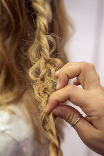 Once you've secured the braid with a clear elastic, go back and pull sections of hair within the braid to create loops in the look.
Once you've secured the braid with a clear elastic, go back and pull sections of hair within the braid to create loops in the look.