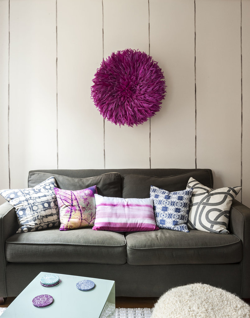 To maximize space, Ali and Lindsay choose side and coffee tables that double as stools for additional seating. To add personality, they hung a magenta juju (African feather headdress) above the sofa.
Photo by  Matthew Williams via LABLstudio
