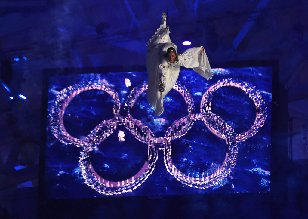 An angelic woman was suspended beside the Olympic rings.
