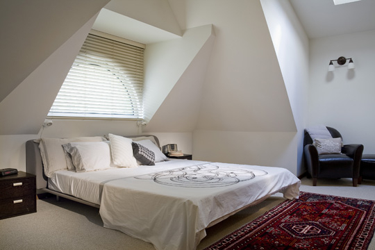 Since the high ceilings and architecture of this bedroom create the focal point, a low headboard was chosen. Though the dark wood nightstands match each other, they're not the same style as the headboard, which keeps it from being too matchy-matchy. The upholstered headboard in subdued gray coordinates with the rug and dark wood.
Since the high ceilings and architecture of this bedroom create the focal point, a low headboard was chosen. Though the dark wood nightstands match each other, they're not the same style as the headboard, which keeps it from being too matchy-matchy. The upholstered headboard in subdued gray coordinates with the rug and dark wood.